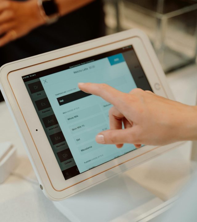 Close-up of a hand interacting with a tablet at a checkout counter, illustrating modern retail technology.